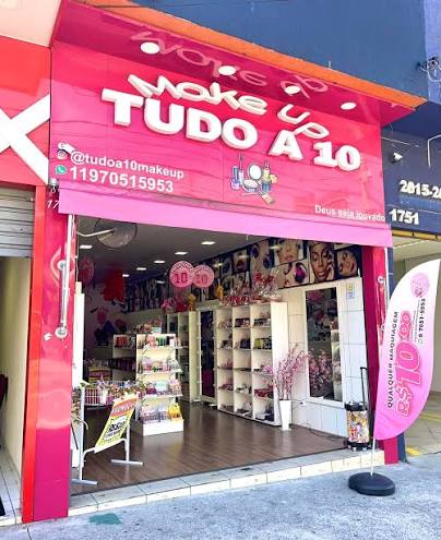 Entrada de uma loja Tudo a 10 Makeup em São Paulo, com fachada rosa e prateleiras de cosméticos.